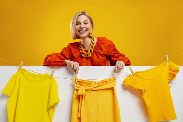 Atraktivní Mladá Žena Visí Barevné Oblečení Prádelní Šňůře Proti Žlutému — Stock fotografie