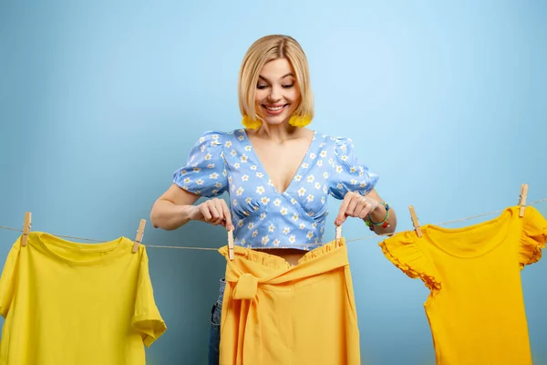 Счастливая Молодая Женщина Вешает Свою Красочную Одежду Бельевую Веревку Голубом — стоковое фото
