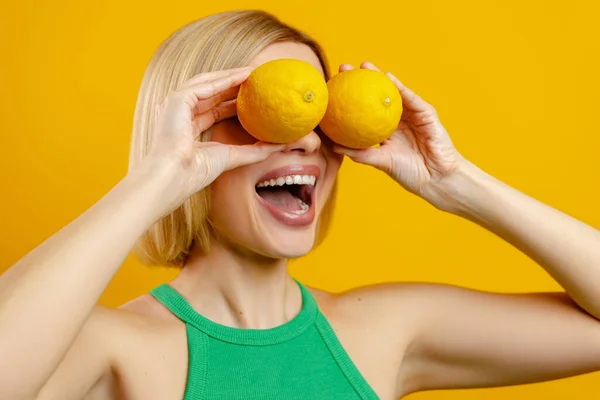 Возбужденная Молодая Женщина Покрывающая Глаза Лимонами Улыбающаяся Желтом Фоне — стоковое фото