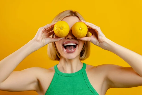 Glückliche Junge Frau Bedeckt Augen Mit Zitronen Vor Gelbem Hintergrund — Stockfoto