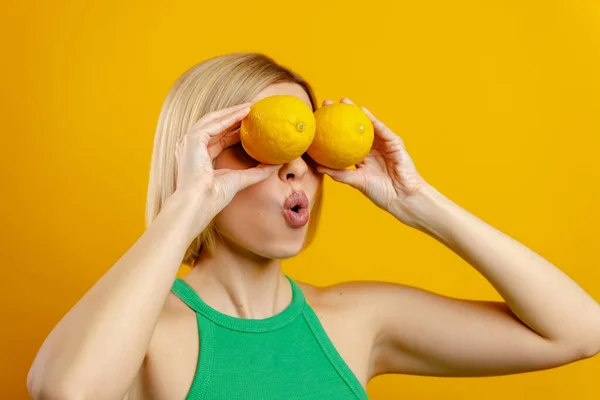 Возбужденная Молодая Женщина Закрывающая Глаза Лимонами Выглядящая Удивленной Желтом Фоне — стоковое фото