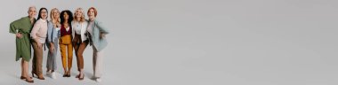 Gri arka plana karşı birleşen çok ırklı, mutlu, olgun kadınlardan oluşan bir grup.