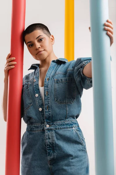 stock image Fashionable young short hair woman in denim clothes standing among colorful paper rolls