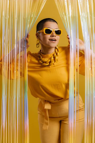 Μοντέρνα Γυναίκα Μοντέρνα Γυαλιά Κοιτάζοντας Μέσα Από Πολύχρωμη Κουρτίνα Κίτρινο — Φωτογραφία Αρχείου