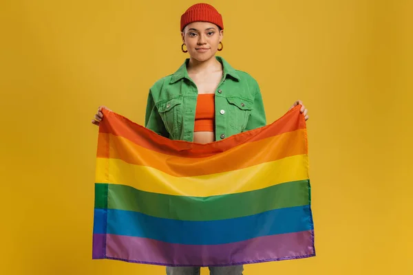 Confident Young Woman Carrying Rainbow Flag While Standing Yellow Background — Stock Photo, Image