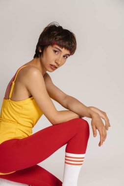 Gri arka planda, eski tarz spor elbiseli genç fit kadın portresi.