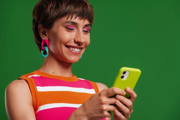 Attraktive Junge Frau Mit Smartphone Und Lächeln Vor Grünem Hintergrund — Stockfoto