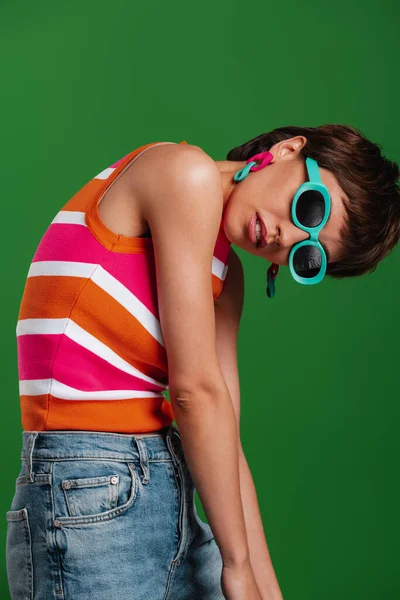 Modna Młoda Kobieta Modnych Okularach Patrząca Kamerę Stojąc Zielonym Tle — Zdjęcie stockowe