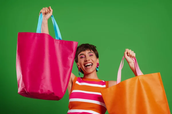 Izgalmas Fiatal Mutatja Színes Bevásárló Táskák Miközben Áll Szemben Zöld — Stock Fotó