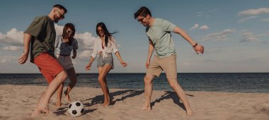 Bir grup genç futbol oynuyor ve sahilde birlikte eğleniyor.