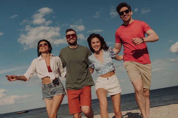 Grupo Amigos Felices Uniéndose Sonriendo Mientras Corren Por Playa Juntos —  Fotos de Stock