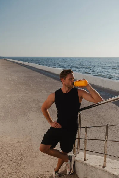 上午户外运动训练后 疲惫男性运动员喝水及欣赏海景的头像 — 图库照片