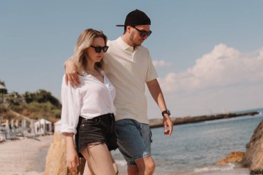 Kumsalda yürürken kucaklaşan romantik bir çift.