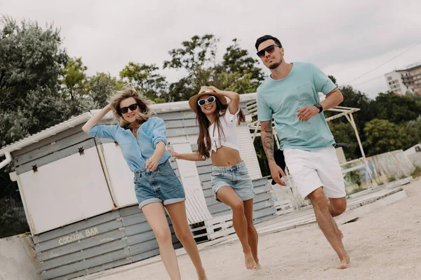3人の幸せな若い友人が一緒にビーチで走っている間 無駄な時間を過ごします — ストック写真