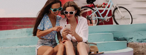 Dos Mujeres Jóvenes Atractivas Mirando Teléfono Inteligente Sonriendo Mientras Están —  Fotos de Stock