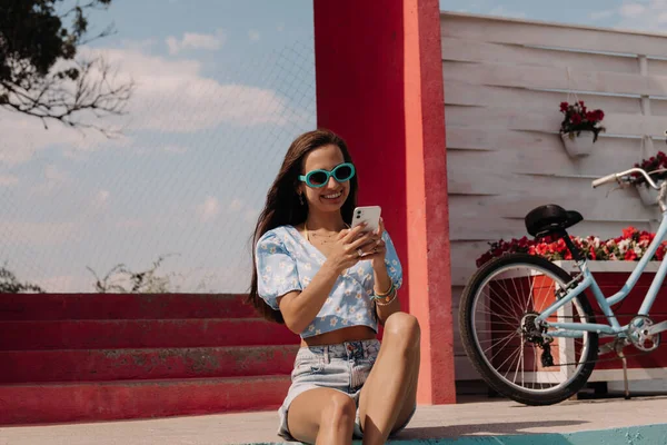 Joyful Young Woman Holding Smart Phone Smiling While Sitting Seaside — Stock Photo, Image