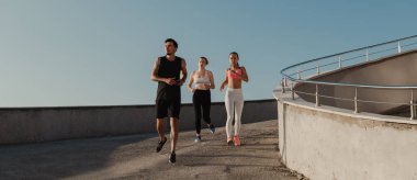 Spor giyimli üç genç, sabah koşularının keyfini çıkarıyorlar.