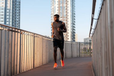 Spor giysileri içinde kendinden emin genç Afrikalı bir adam sabah koşusunun tadını çıkarıyor.