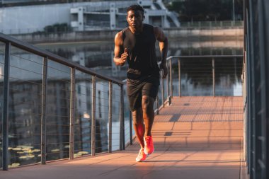 Spor giyimli kendine güvenen genç Afrikalı adam sabah koşusunun tadını çıkarıyor.