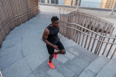 Spor giyimli genç Afrikalı adam üst katta koşarken konsantre olmuş görünüyor.