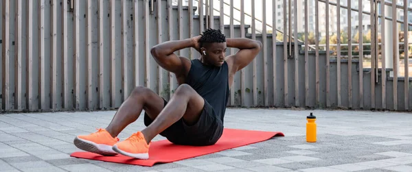 スポーツウェアのハンサムな若いアフリカ人男性は 屋外で運動しながら座っている — ストック写真
