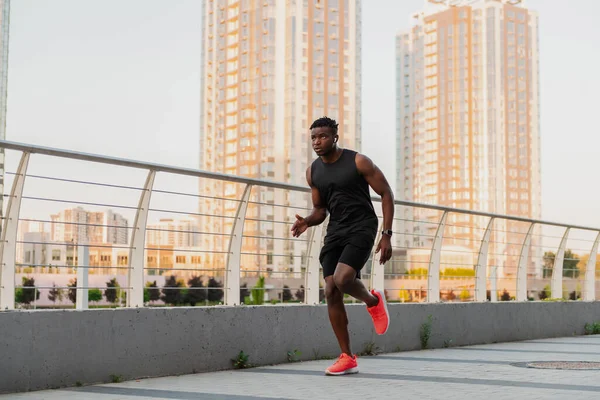 バックグラウンドで街のスカイラインで屋外を実行するスポーツウェアに自信を持ったアフリカ人男性 — ストック写真