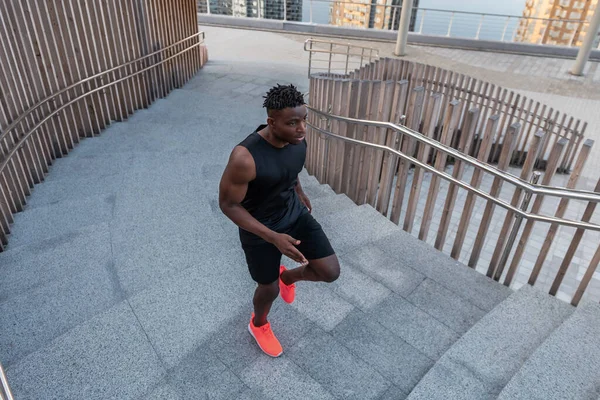 Spor giyimli genç Afrikalı adam üst katta koşarken konsantre olmuş görünüyor.