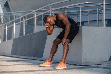 Spor kıyafetleri içinde spor antrenmanlarından sonra dinlenen yorgun Afrikalı bir adam.