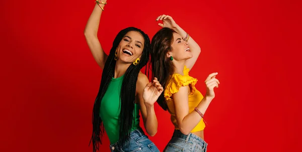 Dos Mujeres Jóvenes Atractivas Ropa Colorida Bailando Sobre Fondo Rojo —  Fotos de Stock