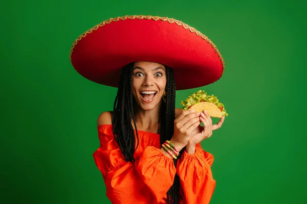 Sorprendida Joven Mexicana Sombrero Sosteniendo Taco Sonriendo Sobre Fondo Verde — Foto de Stock