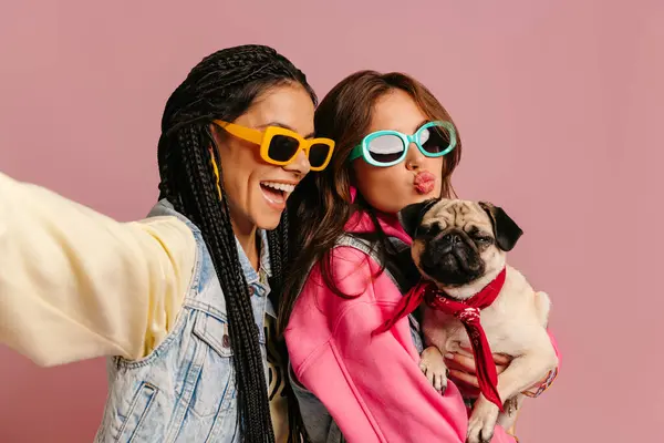 Két Vidám Fiatal Divatos Szemüvegben Aranyos Mopsz Kutyát Cipelve Szelfit — Stock Fotó