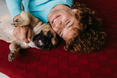 Mutlu genç adamın sevimli köpeğini okşamasının en iyi görüntüsü evde yerde birlikte yatarken.