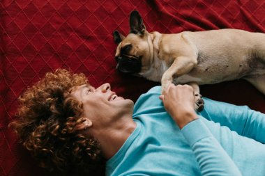 Mutlu genç adamın sevimli köpeğini okşamasının en iyi görüntüsü evde yerde birlikte yatarken.