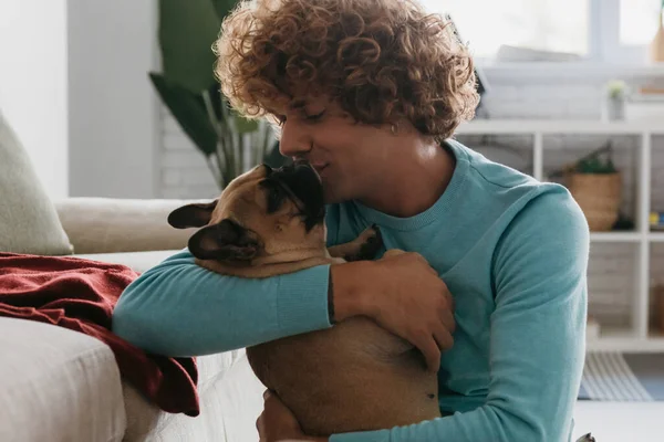 Šťastný Mladý Kudrnatý Muž Objímající Líbající Svého Roztomilého Psa Při — Stock fotografie