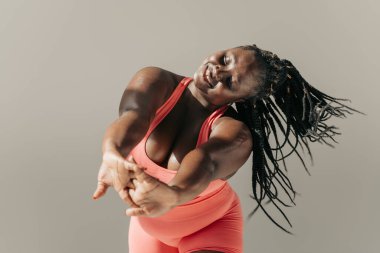 Neşeli Afrikalı şişman kadın spor giyim bölümünde spor salonlarında esneme egzersizleri yapıyor.