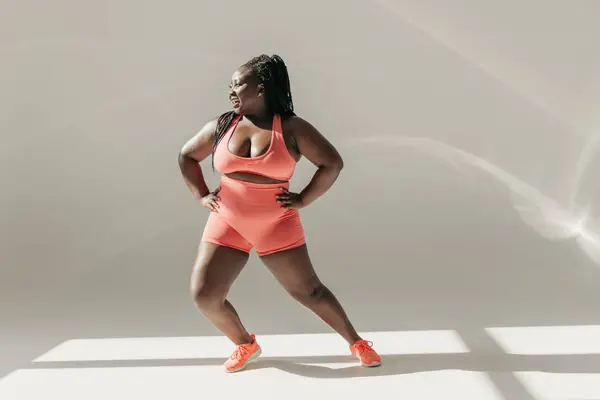 stock image Full length of happy African plus size woman in sportswear warming up before training in fitness studio