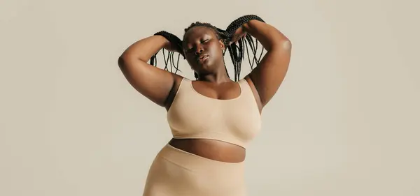 stock image Calm African plus size woman in underwear radiating self-love while standing on studio background