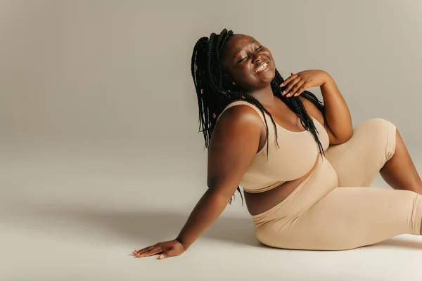 Joyful Curvy African Woman Sportswear Radiating Self Love While Sitting — Stock Photo, Image