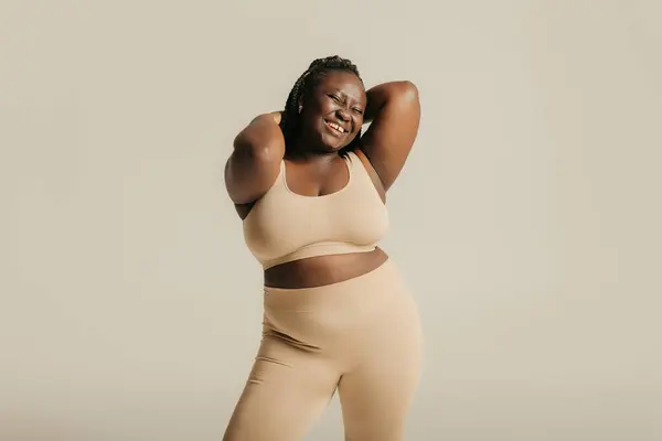 穿着内衣裤的快乐的非洲女人在工作室的背景下把爱辐射到她的身体上 — 图库照片