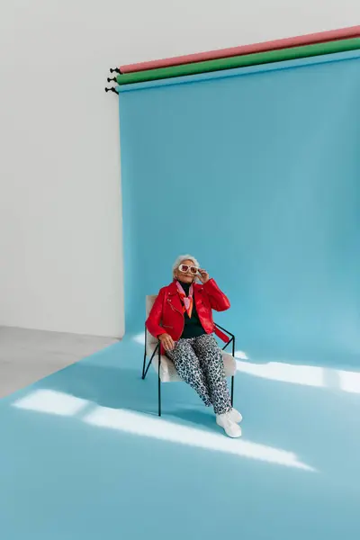 Μοντέρνα Ηλικιωμένη Γυναίκα Μοντέρνα Ρούχα Κάθεται Άνετη Καρέκλα Φόντο Μπλε — Φωτογραφία Αρχείου