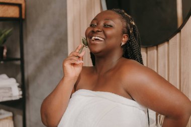 Mutlu ve cüsseli Afrikalı kadın. Havluyla masaj yapıyor. Tuvalette yuvarlanıyor.