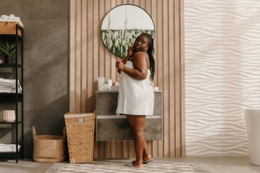 Güzel, iri yapılı, havluya sarılı Afrikalı bir kadın. İç tuvalette güzel bir sabah geçiriyor.