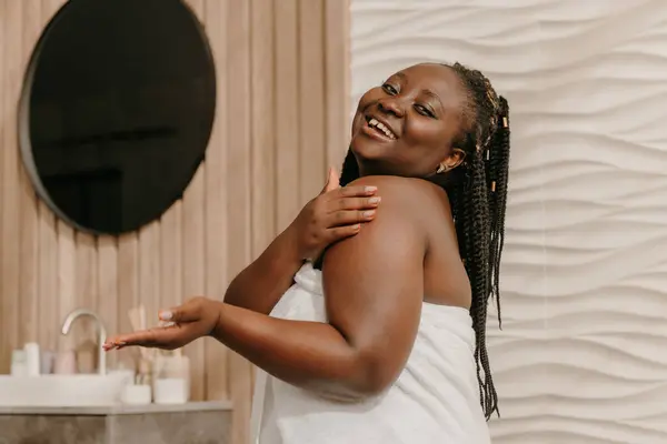 Happy Velikost Africké Ženy Pokryté Ručníkem Použití Kosmetické Krém Rameni — Stock fotografie