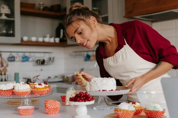 Happy Young Female Pastry Chef Applying Whipped Cream While Making — Stock Photo, Image