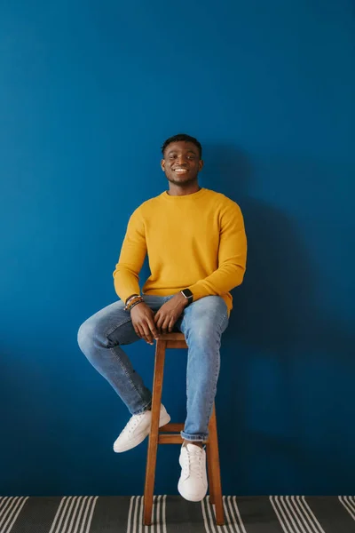 Розслаблений Молодий Африканський Чоловік Повсякденному Одязі Виглядає Щасливим Сидячи Стільці — стокове фото