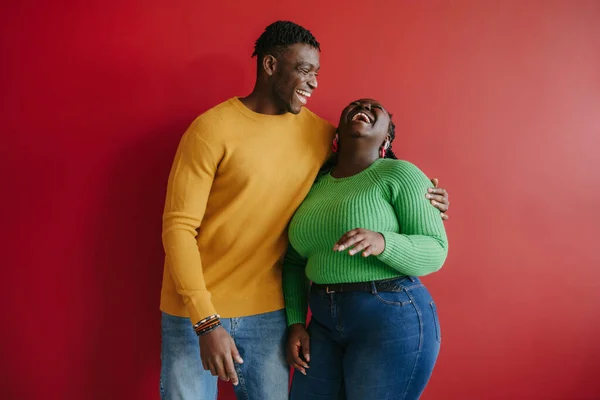 Beautiful Young African Couple Embracing Laughing While Standing Red Background — Stock Photo, Image