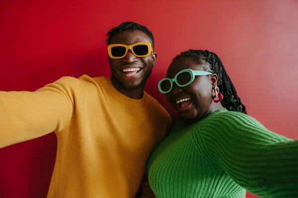 Modieus Jong Afrikaans Paar Trendy Bril Omarmen Glimlachen Rode Achtergrond — Stockfoto