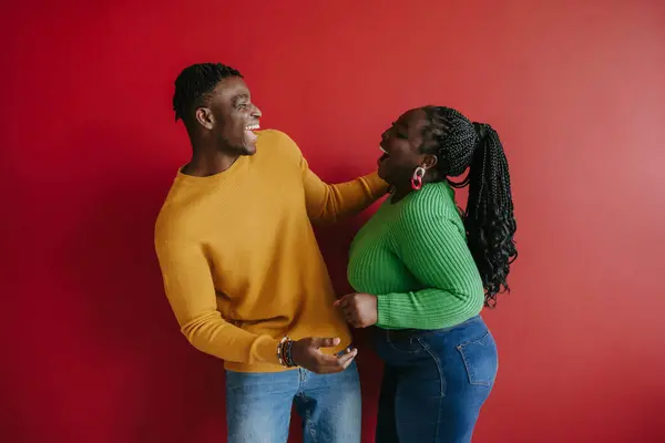 Sarılıp Birbirlerine Kırmızı Arka Planda Bakan Mutlu Genç Afrikalı Çift — Stok fotoğraf