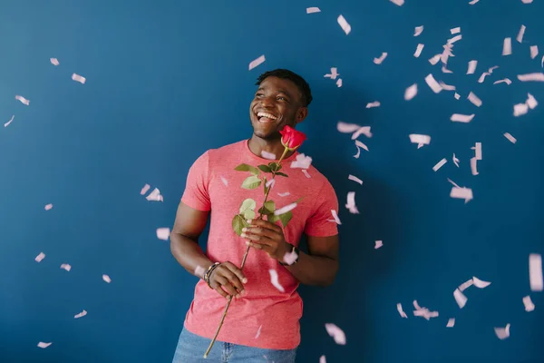 Happy Young African Man Holding Single Rose Smiling While Confetti — Stock Photo, Image