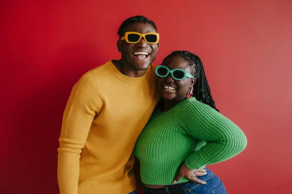 Fashionable Young African Couple Trendy Glasses Embracing Smiling Red Background — Stock Photo, Image